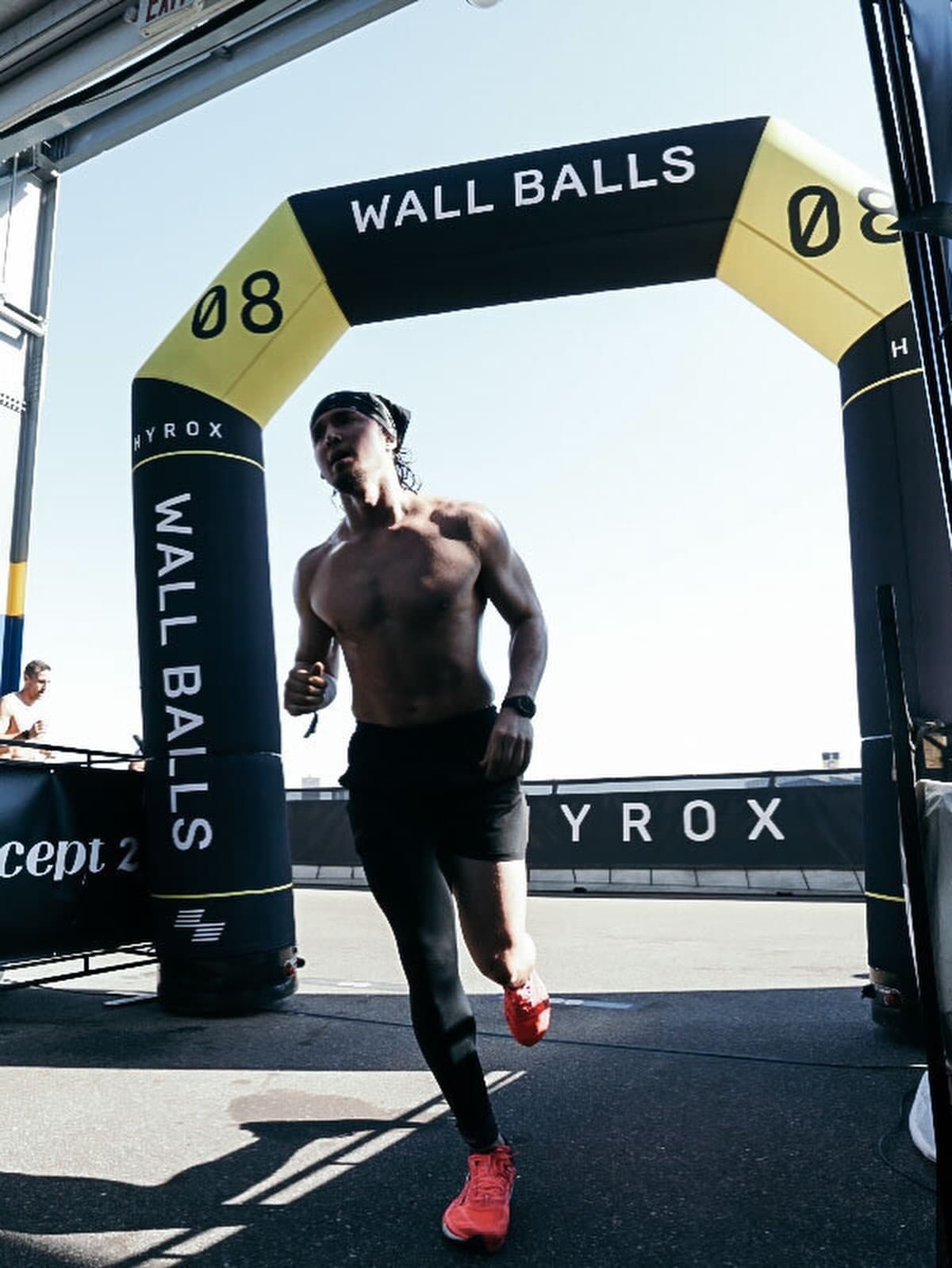 An athlete running under the inflatable Station 08 wall balls arch