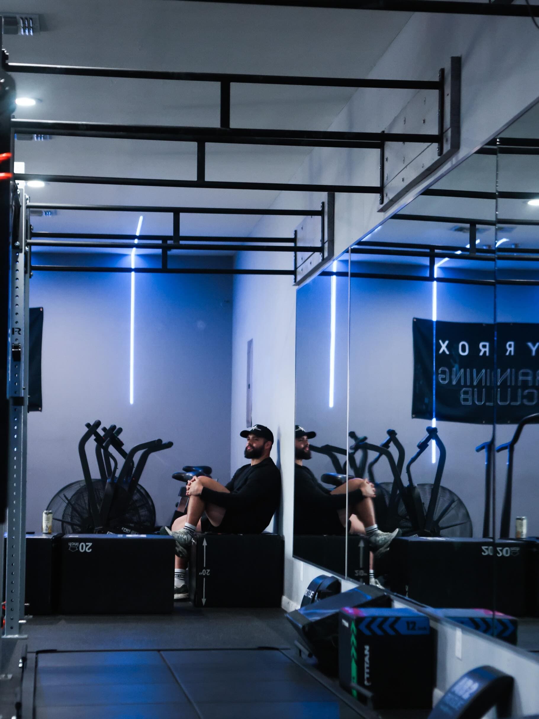 An athlete resting on a plyo box in the HYROX training corner of the studio