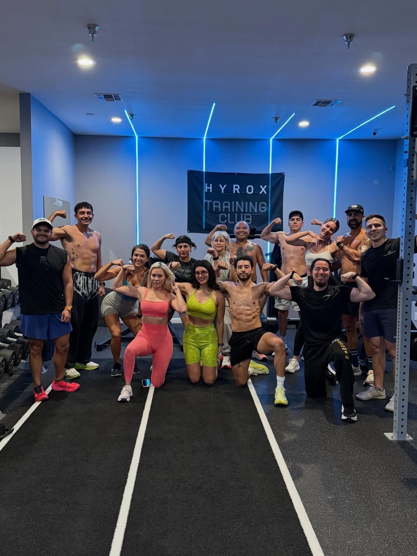 A full class flexing under the blue neon and the HYROX banner