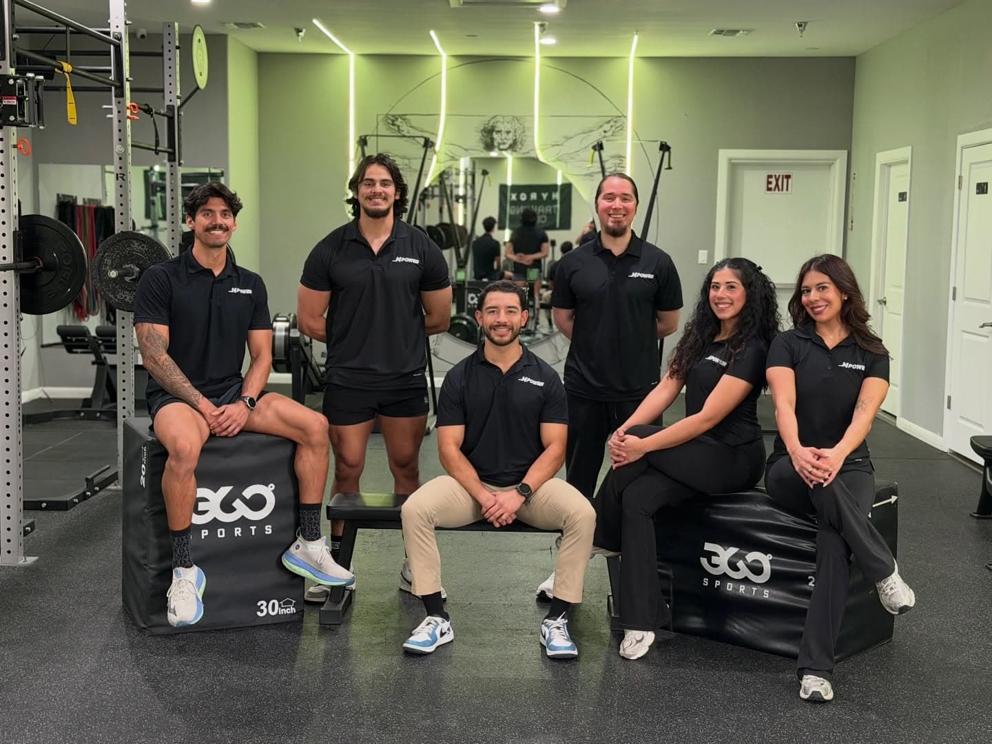 The six Mpower coaches seated on plyo boxes in the studio